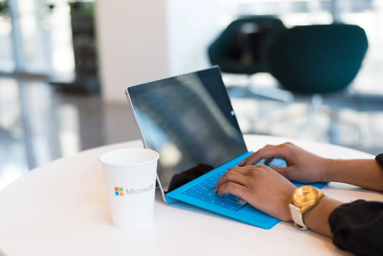 Une personne travaillant sur un pc windows surface avec microsoft copilot et un gobelet microsoft